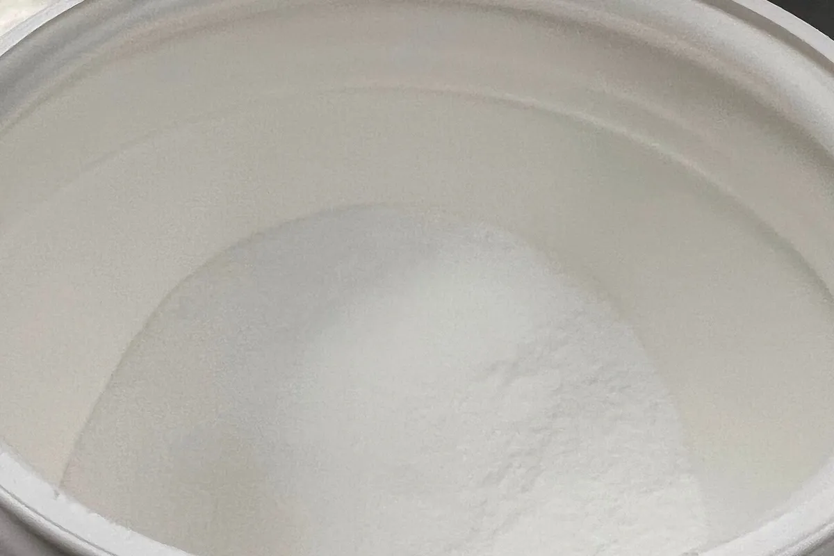 An open tub filled with fine white creatine powder