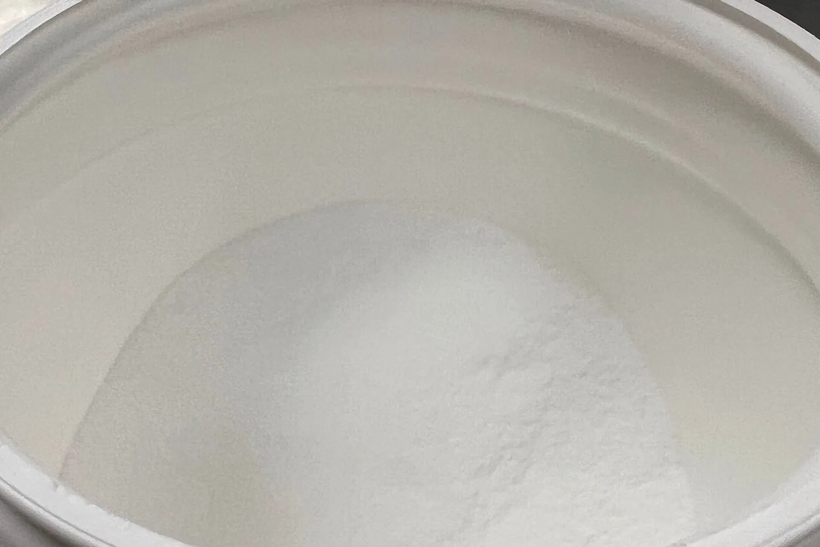 An open tub filled with fine white creatine powder