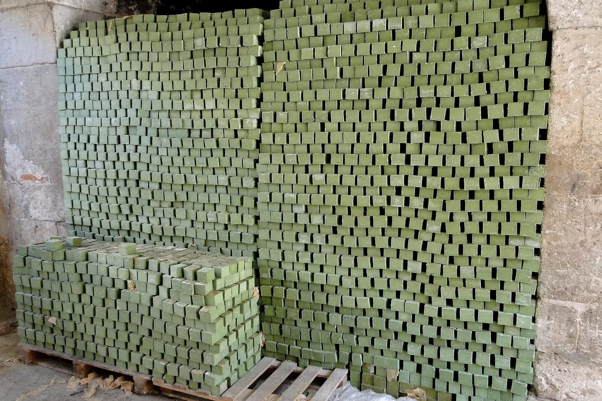 Hundreds of olive-green bars of traditional soap stacked into tall walls to cure.