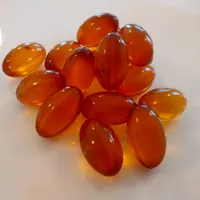 A small cluster of glossy amber softgel capsules on a white surface.