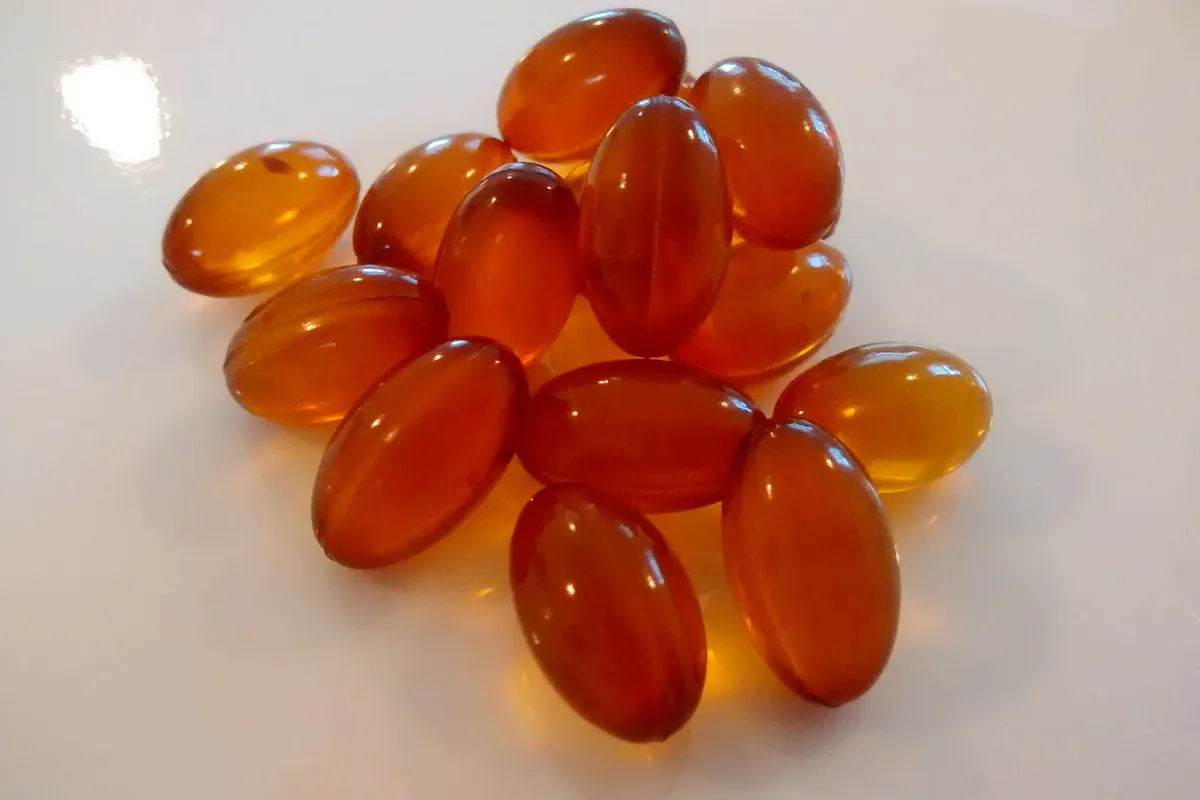 A small cluster of glossy amber softgel capsules on a white surface