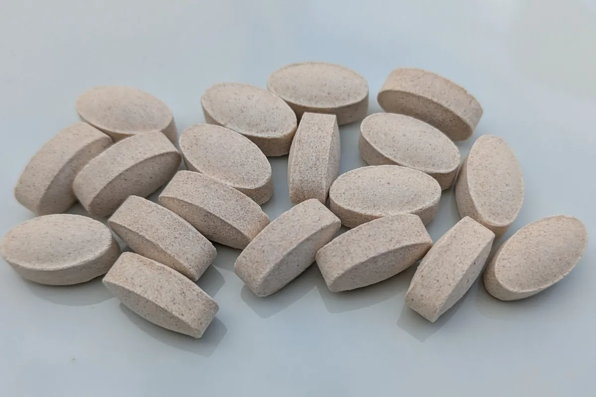 A small heap of oval speckled tablets on a pale grey surface