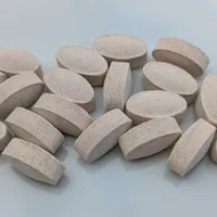 A small heap of oval speckled tablets on a pale grey surface.