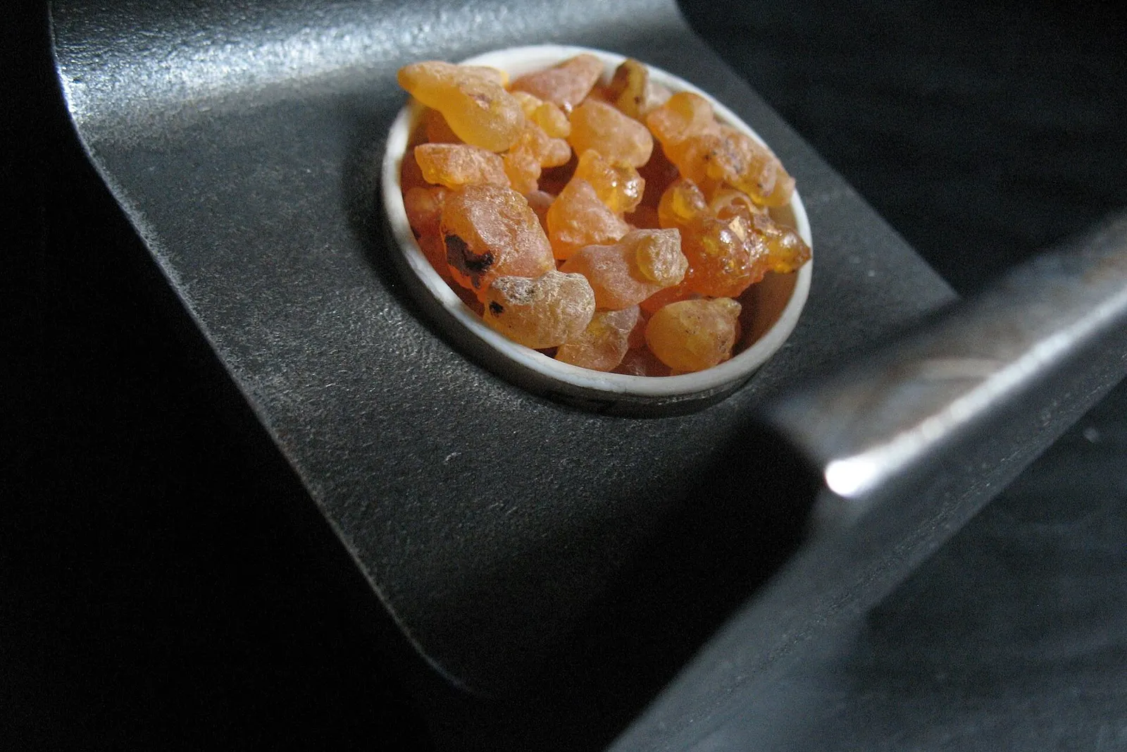 Translucent amber pieces of frankincense resin in a small round dish.