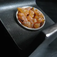 Translucent amber pieces of frankincense resin in a small round dish.