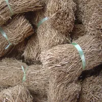 Bundles of dried, fibrous vetiver roots tied together and stacked for sale.