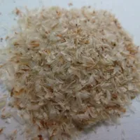 A small pile of pale, flaky psyllium seed husks on a light surface.
