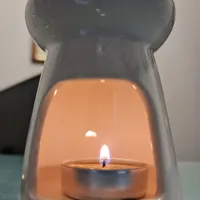 A tealight glowing inside a white ceramic oil burner.